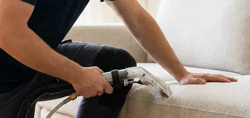 Professional upholstery cleaner deep-cleaning a fabric sofa with a handheld extraction tool, Sarasota, FL.